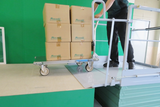 トラックから荷をおろす・積み込む、移動式段差解消用シザーリフト、段差らく~だ、渡り板により移動